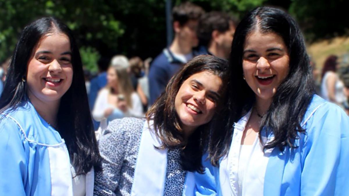 Twins Nathalie, Amaya and Nicole Martinez wearing graduation gowns.